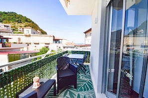 Ein Balkon mit Tisch und Stühlen, einem Dekoelement und Blick auf eine Hügelkuppe mit Gebäuden.