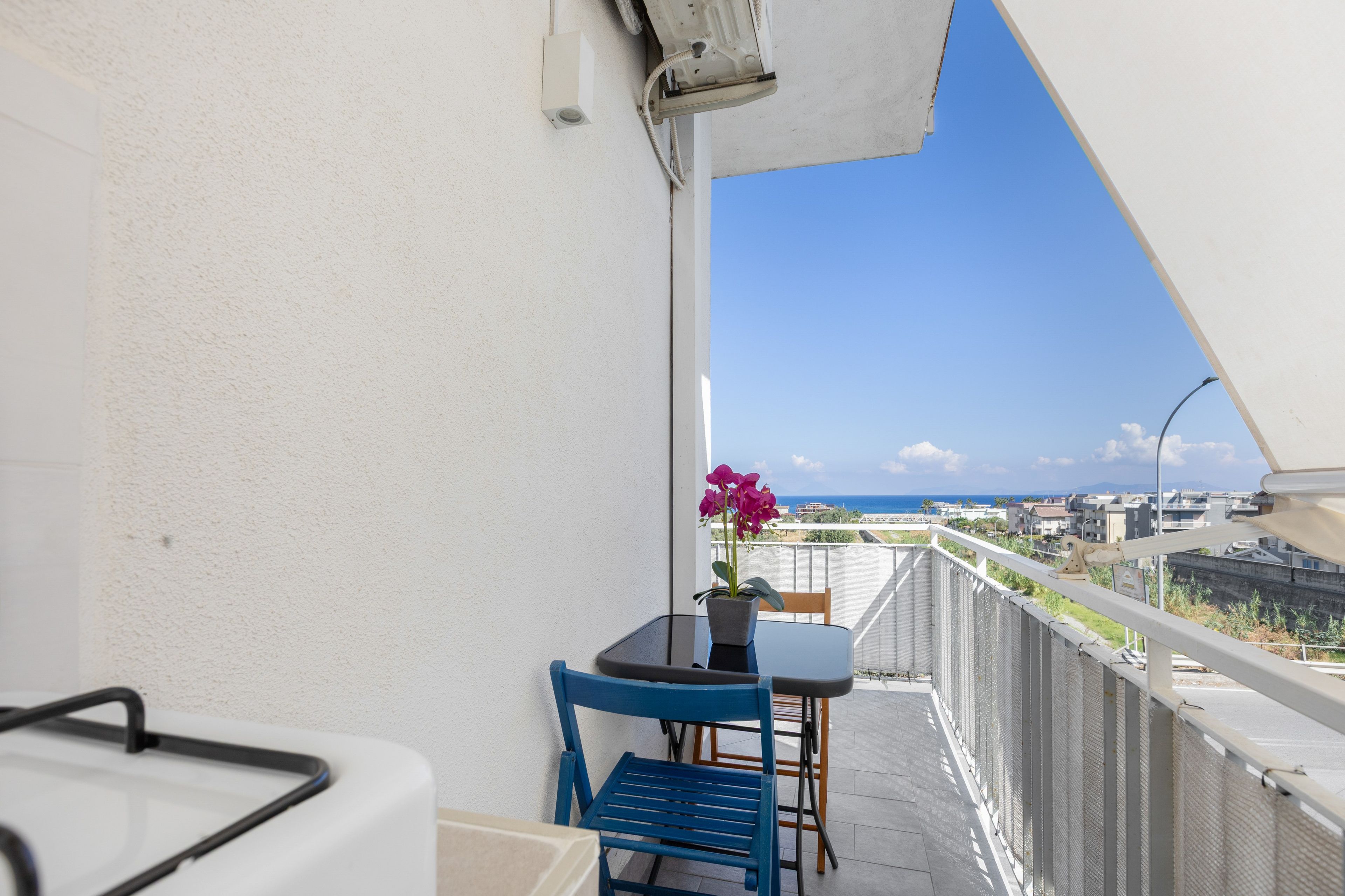Un balcone con tavolo, sedie e una pianta in vaso.