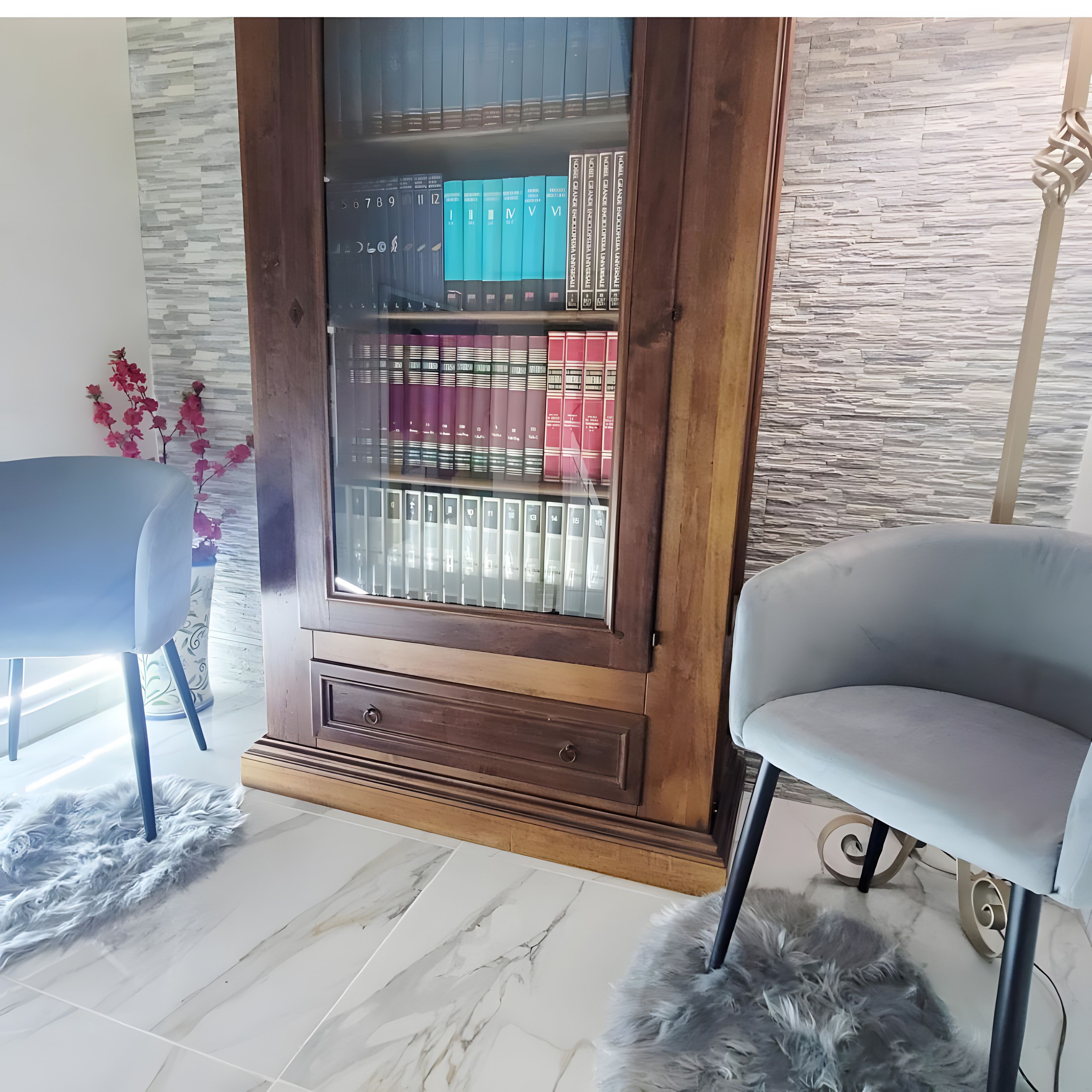 Um quarto com uma grande estante de madeira repleta de livros, uma poltrona confortável, uma cadeira menor e um tapete macio.