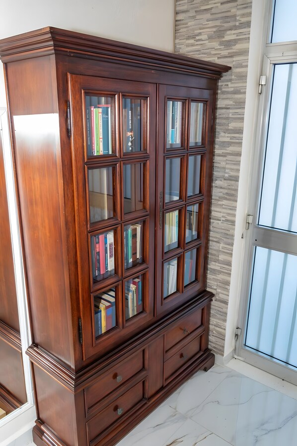 A wooden bookcase with multiple shelves and glass doors, positioned next to a sliding glass door.