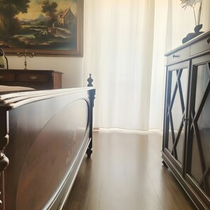 A bedroom with a bed, a dresser, and a painting on the wall.