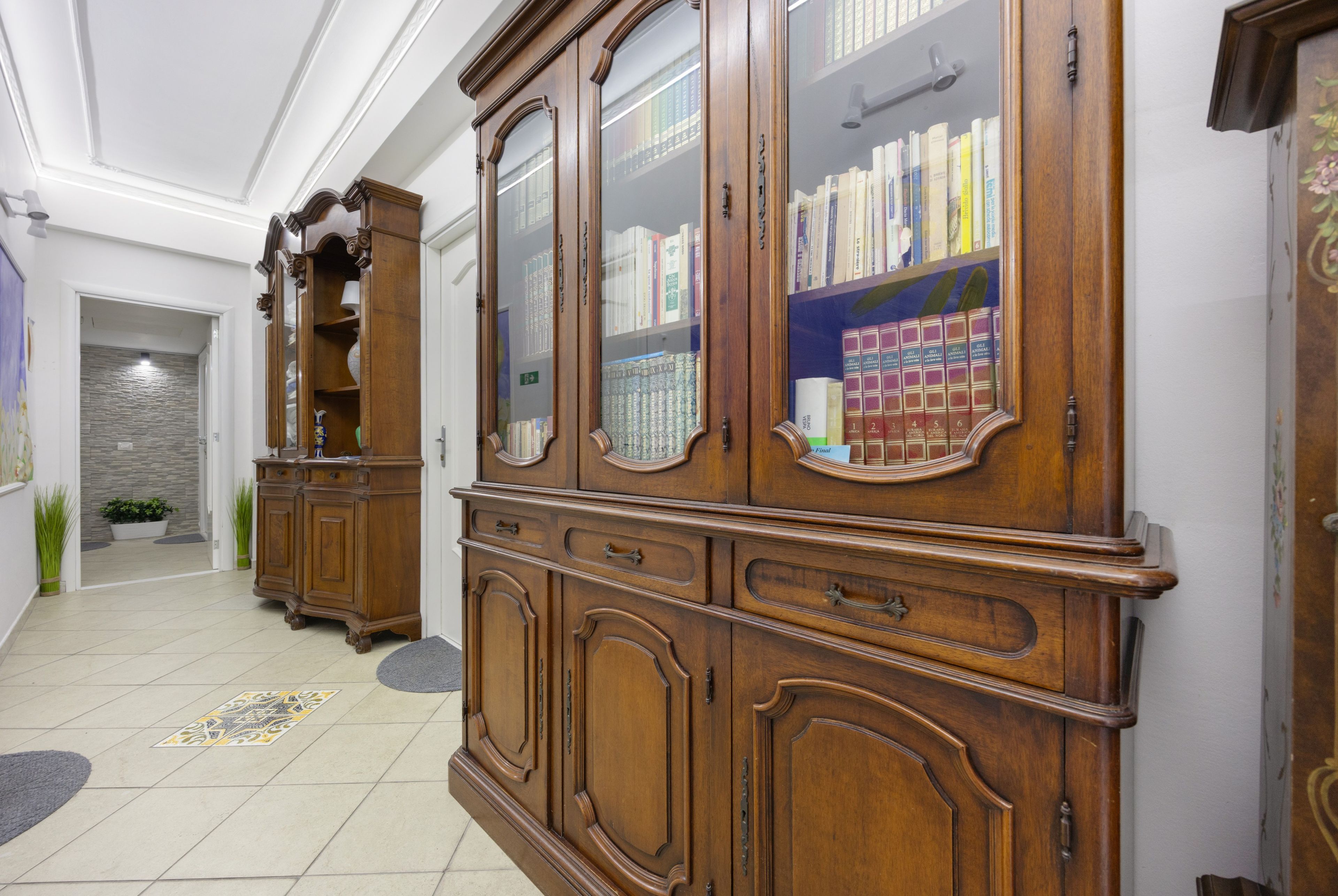 A hallway with wooden bookcases and a tiled floor.