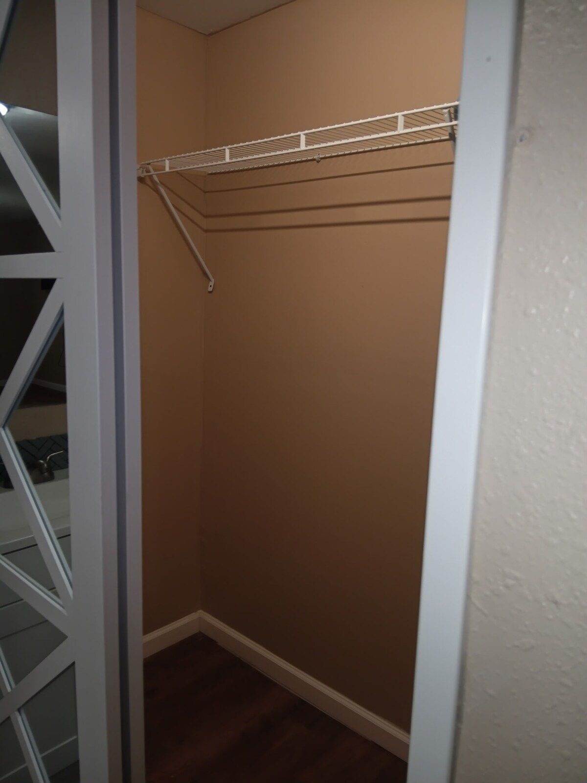 A closet with a white metal shelf and a white door frame.