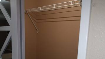 A closet with a white metal shelf and a white door frame.
