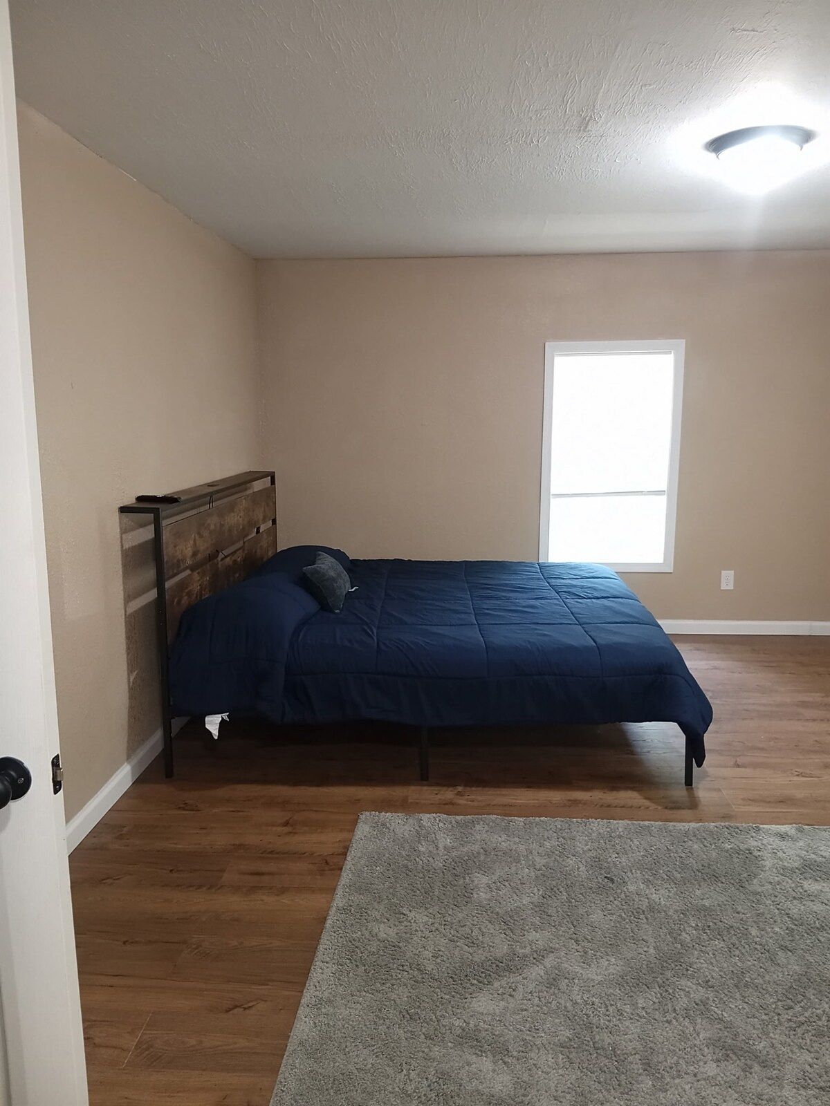 A bedroom with a bed, a window, and a door.