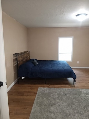 A bedroom with a bed, a window, and a door.