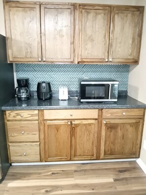A kitchen with wooden cabinets, a microwave, a coffee maker, and a toaster.