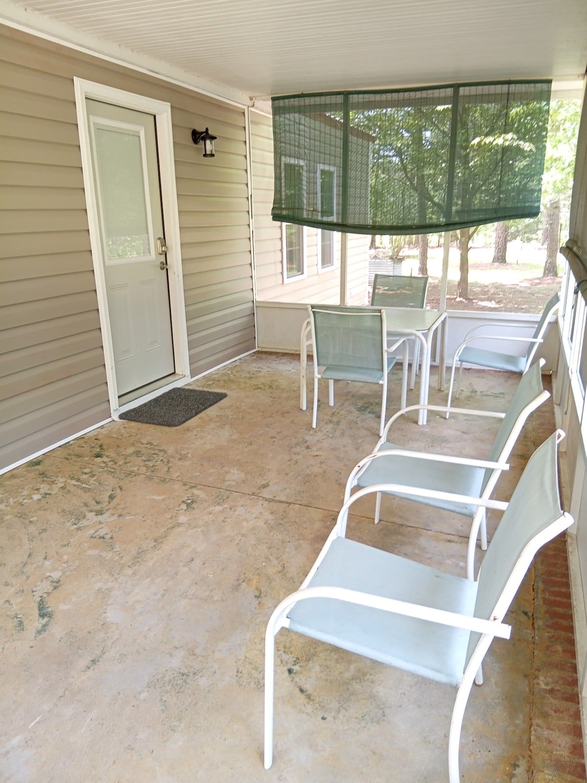 A covered patio with a door, a bench, and a screened area.