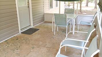 A covered patio with a door, a bench, and a screened area.