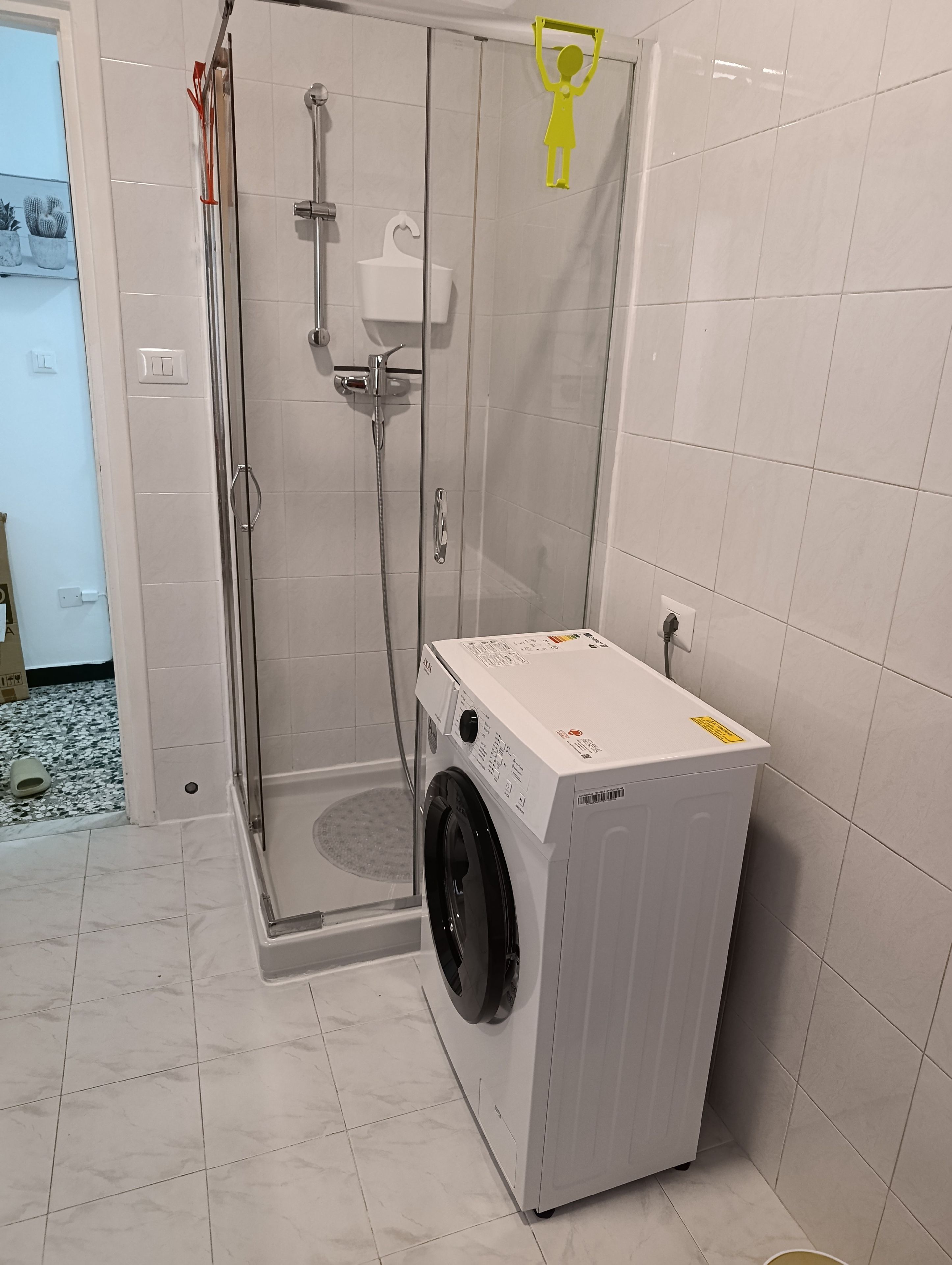 Ein Badezimmer mit Duschkabine, Waschmaschine und Toilette.