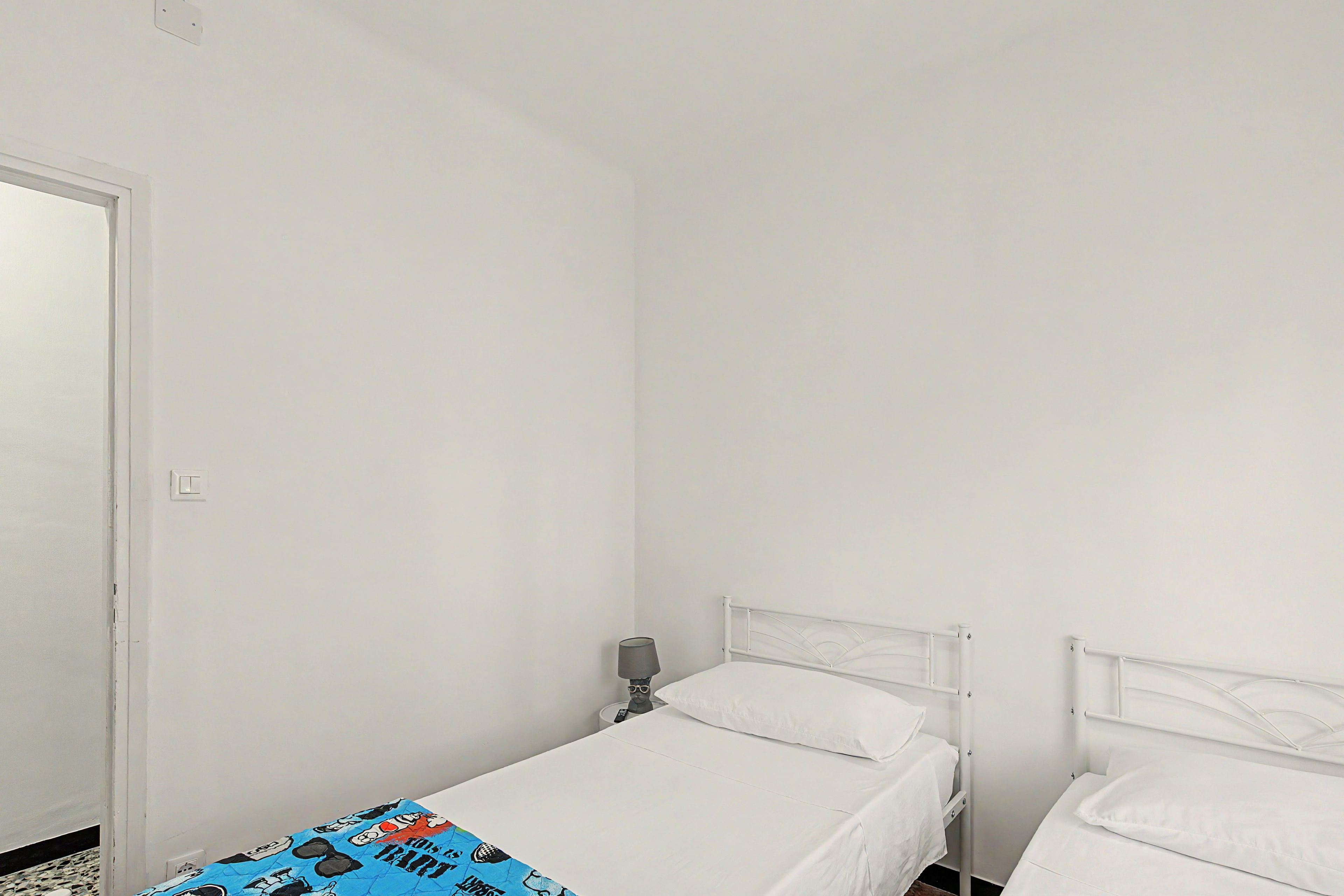 Een eenvoudige, schone kamer met twee bedden en een nachtkastje.