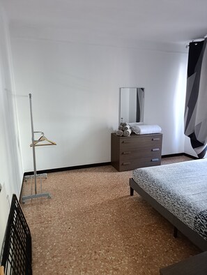 Une chambre à coucher comprenant un lit, une commode, un miroir et un portant à vêtements.