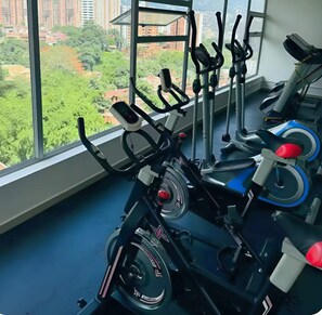 A gym with stationary bikes and a view of a cityscape through large windows. - "Modern Apartment in Sabaneta with a Panoramic View" (Sabaneta)
