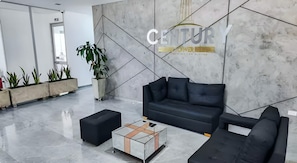 A modern lobby with a black leather sofa, a coffee table, and potted plants. - "Modern Apartment in Sabaneta with a Panoramic View" (Sabaneta)