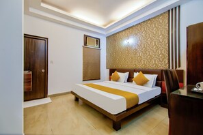 A hotel room with a large bed, a wooden headboard, a desk, and a patterned wall. - JADSTAR RESIDENCY (New Delhi)
