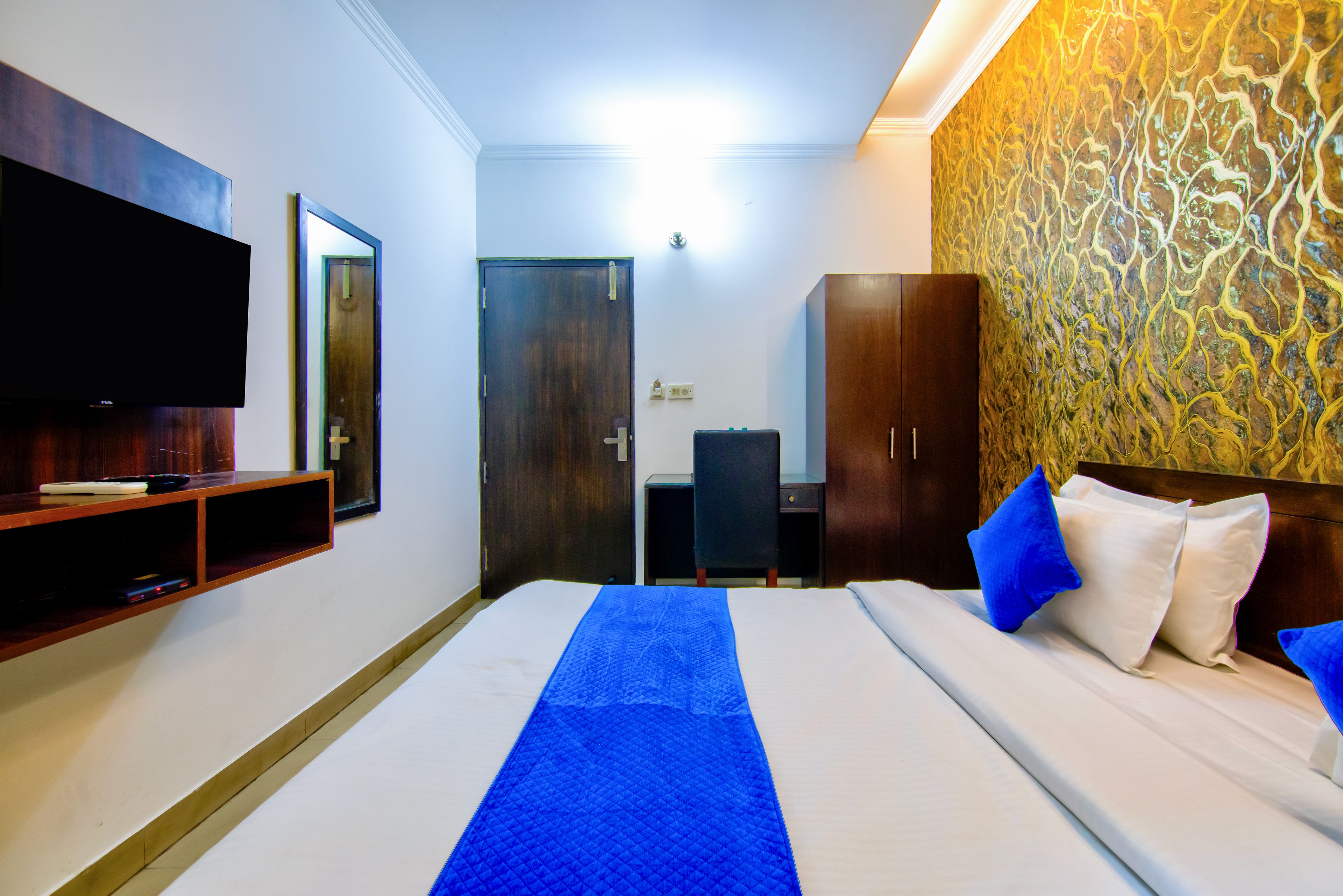 Una habitación de hotel con cama, televisor en la pared, armario y pared con diseño.
