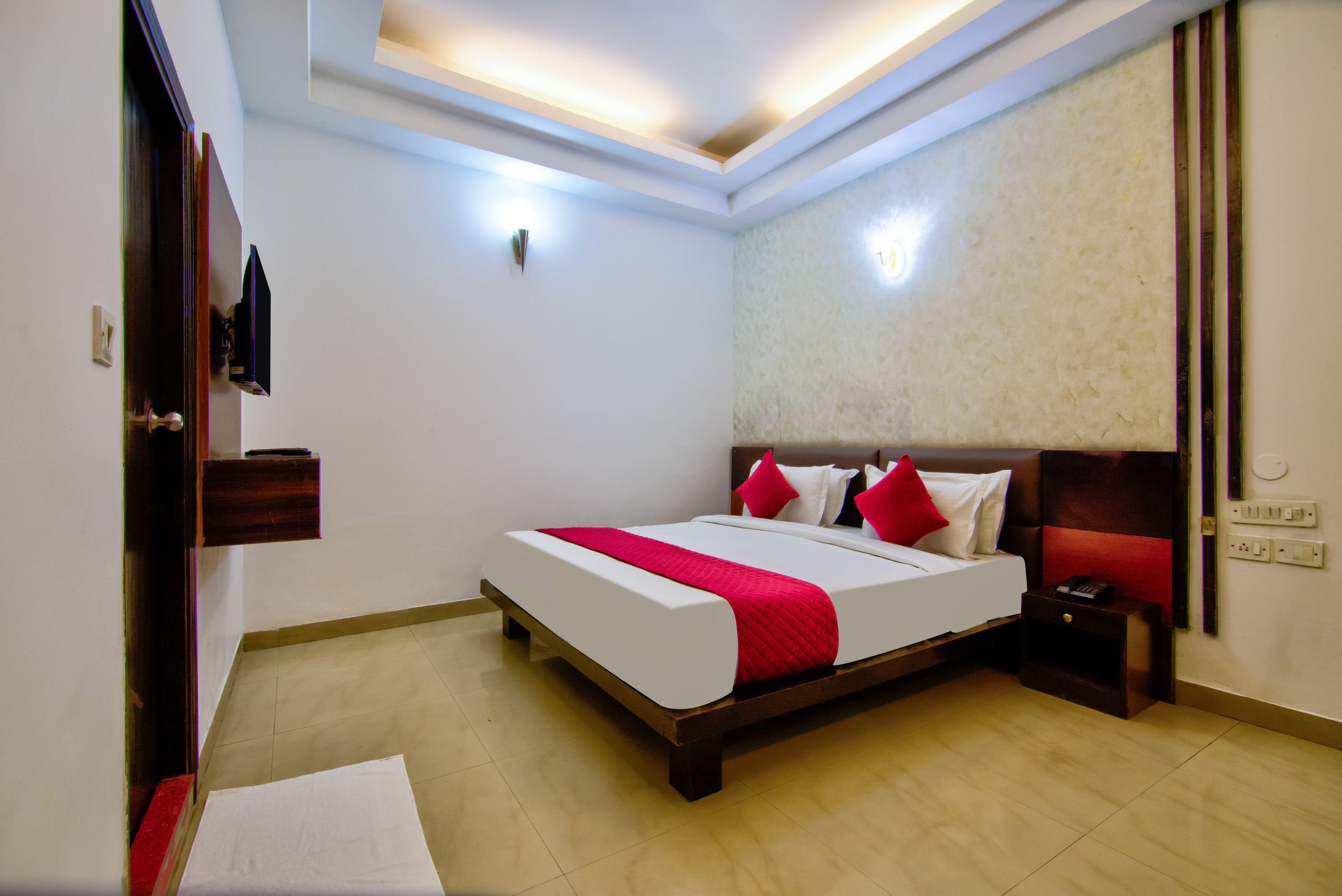 A hotel room with a bed, bedside table, and a wall-mounted TV.