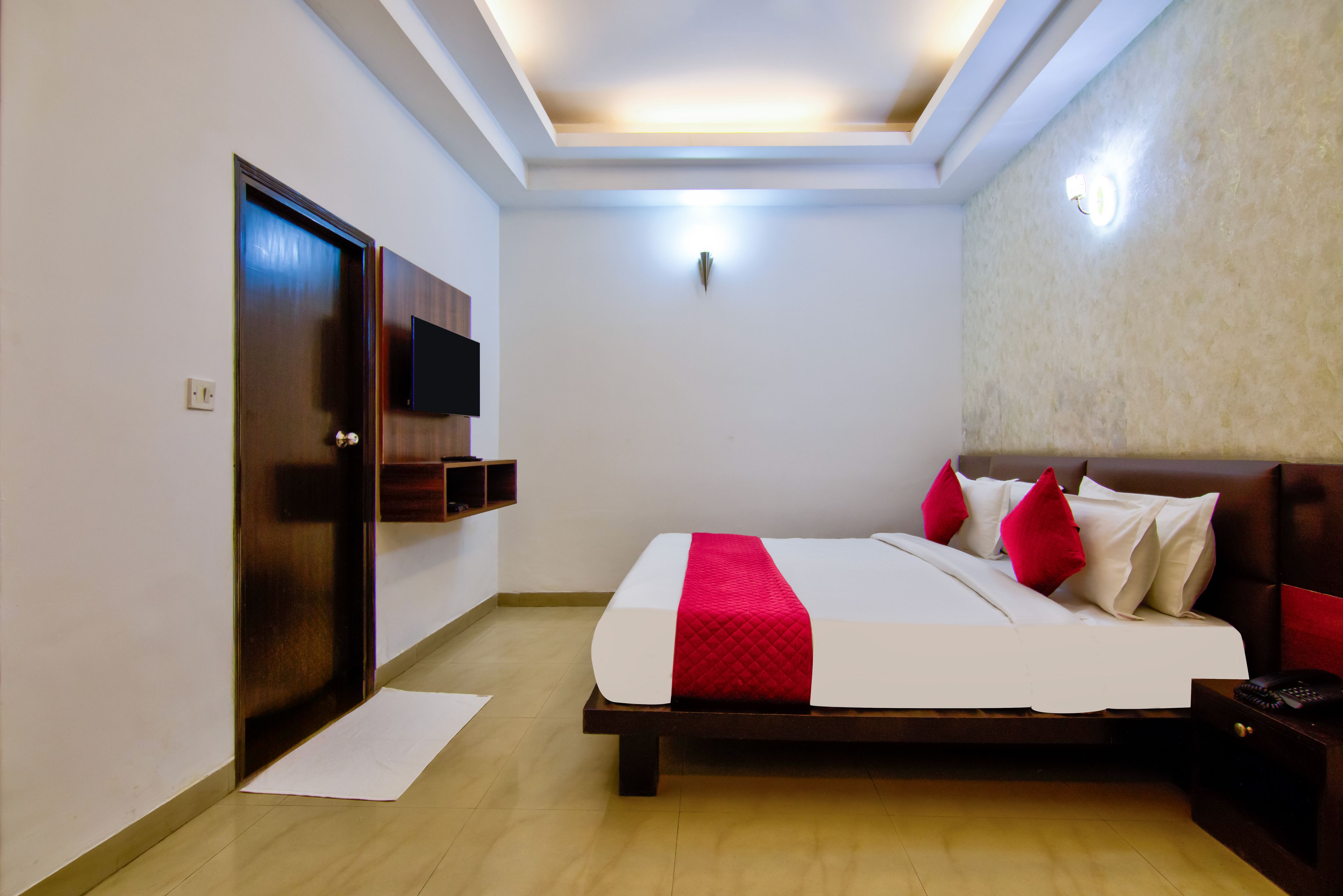 A hotel room with a bed, a television, a bedside table, and a nightstand.