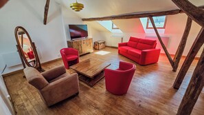 Un salón estilo loft con piso de madera, una mesa de centro de madera, sofás rojos y una televisión.
