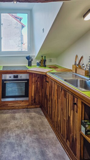 Een keuken met houten kastjes, een roestvrijstalen spoelbak en een inbouwoven.
