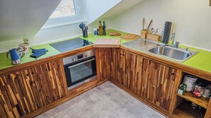 Eine Küche mit Holzausstattung, einem Einbauofen, einem Spülbecken und einem Fenster über der Arbeitsplatte.