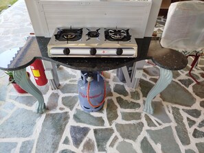 A gas stove with two burners and a gas cylinder beneath it.