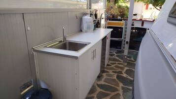 A compact kitchen with a sink, cabinets, and a small trash bin.