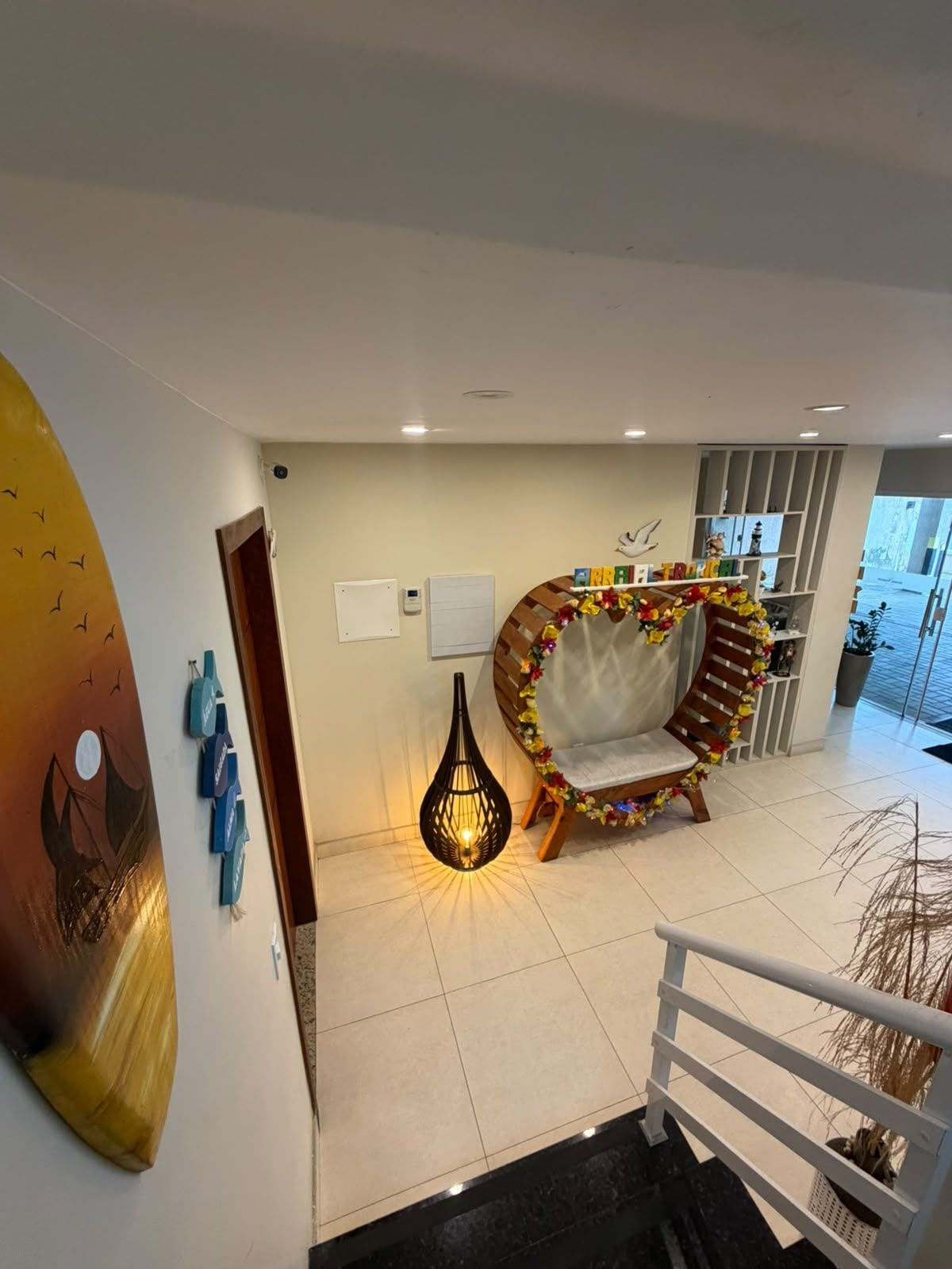 A modern interior with a staircase, a decorative chair, a wall art piece, and a hanging light fixture.