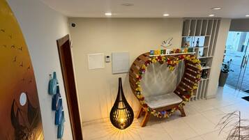 A modern interior with a staircase, a decorative chair, a wall art piece, and a hanging light fixture.