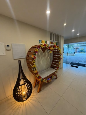 A reception area with a wooden bench adorned with colorful flowers, a hanging light fixture, and a whiteboard on the wall. - Pousada Arraial Tropical (Arraial do Cabo)