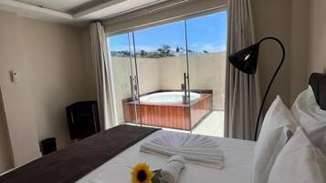 A hotel room with a large bed, a view of the outdoors, a balcony, and a modern lamp.