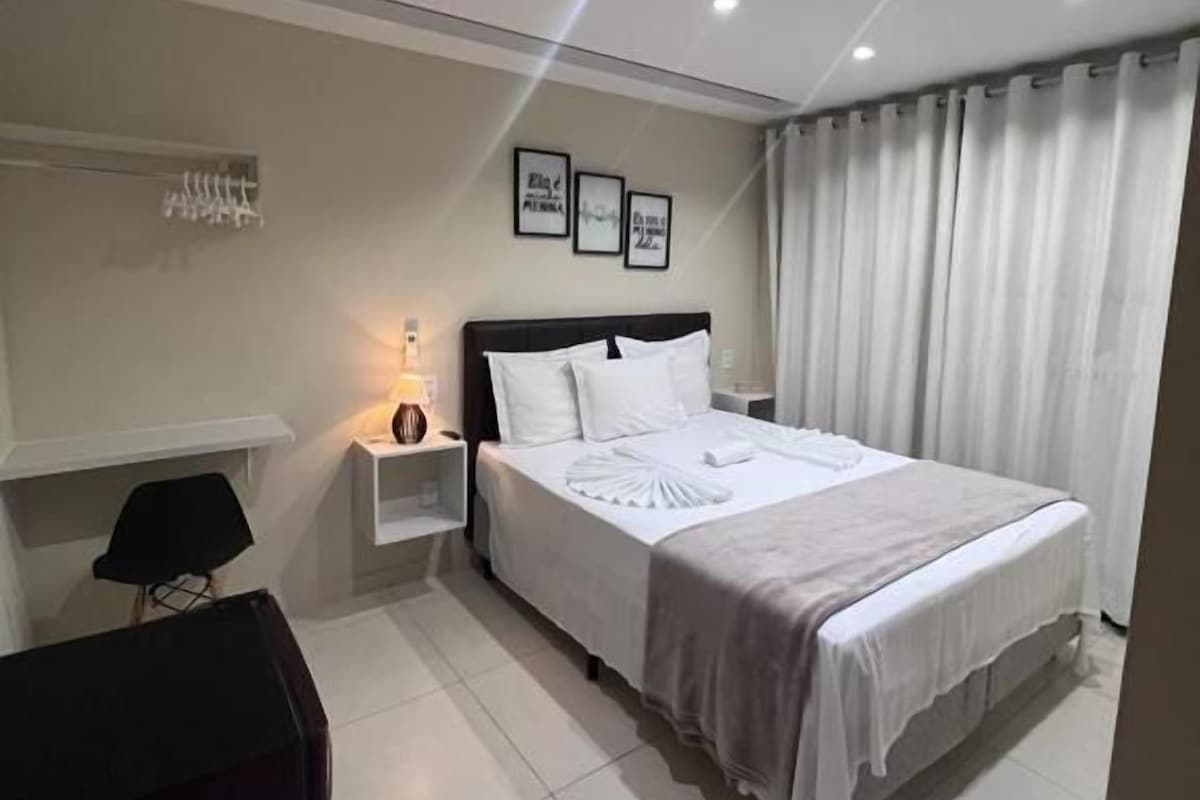 A bedroom with a bed, bedside tables, a lamp, and curtains.
