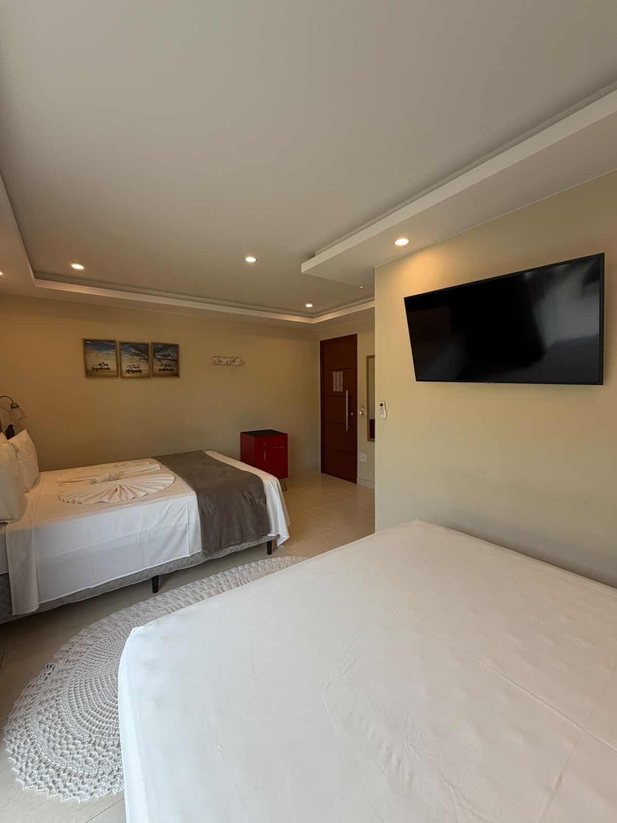 Un dormitorio con dos camas, un televisor montado en la pared y un armario rojo.