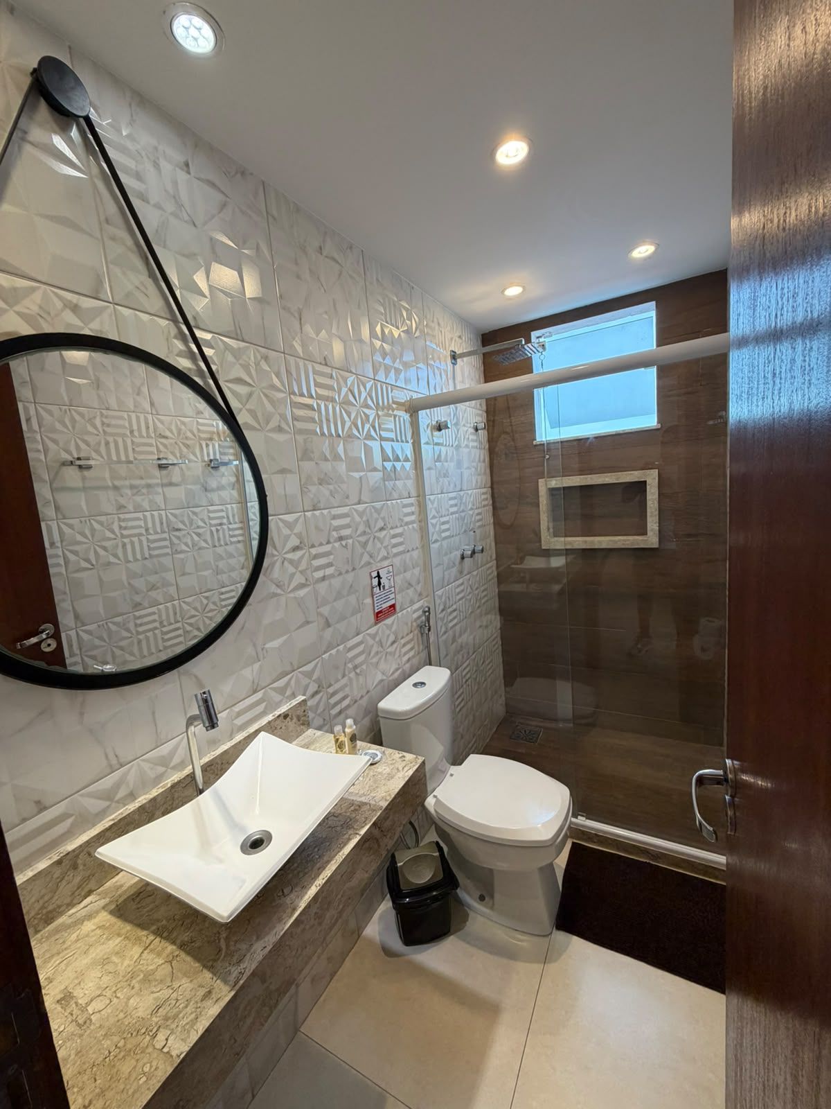 Un baño moderno con lavamanos, inodoro y zona de ducha blancos.