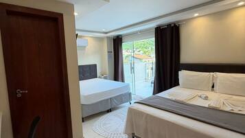 A hotel room with a bed, a desk, and a chair. There is a door and a window with curtains.