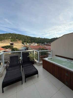 A rooftop terrace with a hot tub, two lounge chairs, and a view of a hillside. - Pousada Arraial Tropical (Arraial do Cabo)