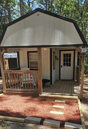 A small, single-story building with a porch, a door, and a window. - The Marie: Cozy East Texas Stay Near Great Fishing (Quitman)