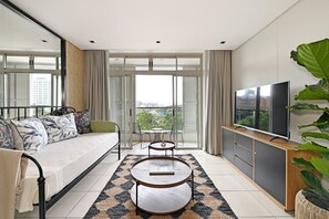 A modern living room with a sofa, a coffee table, a TV, and a balcony with a view of the city. - Modern Apartment | Secure and Spacious (Cape Town)