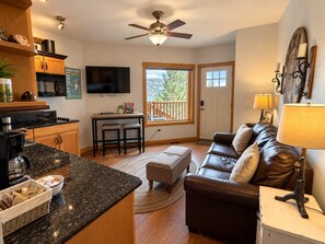 A modern living room with a fireplace, a sofa, a coffee table, and a television. - Emerald Mountain 28C | Couples Retreat at Mary’s Lake (Estes Park)