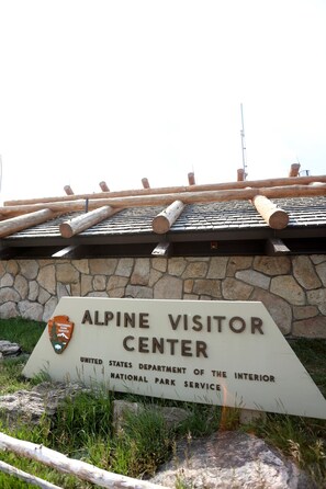 Schild für das Alpine Visitor Center, im Hintergrund eine Steinmauer und Holzbalken.