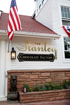 A building with a sign that reads 'The Stanley Chocolate Factory' and an American flag. - Emerald Mountain 28C | Couples Retreat at Mary’s Lake (Estes Park)