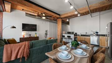 Um espaço de estar moderno com área de jantar, cozinha e assentos.