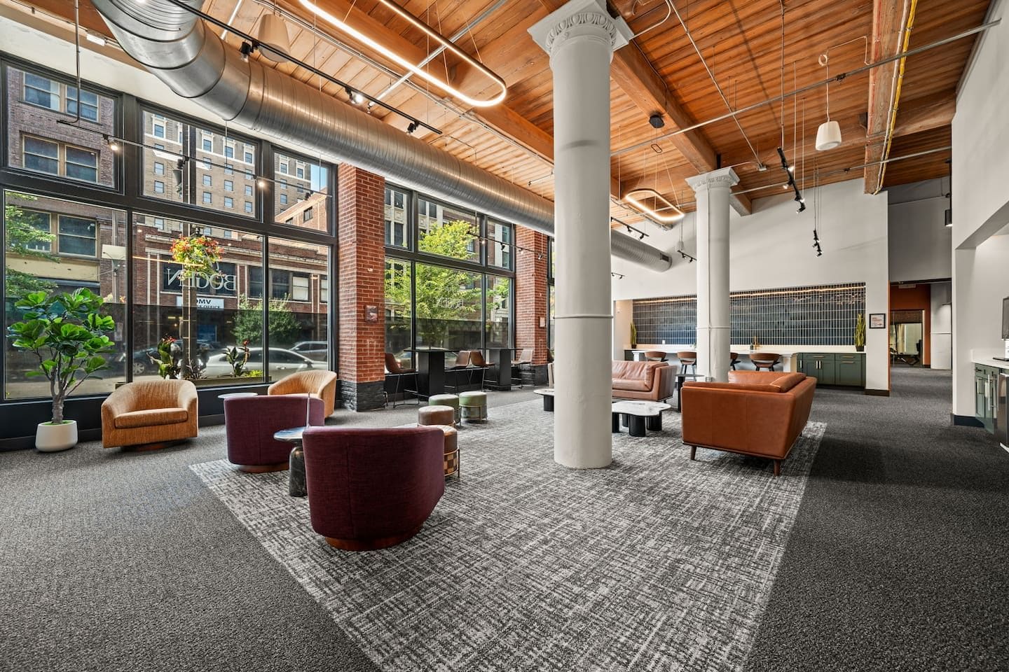 A spacious lobby with large windows, a brick wall, and modern seating arrangements.