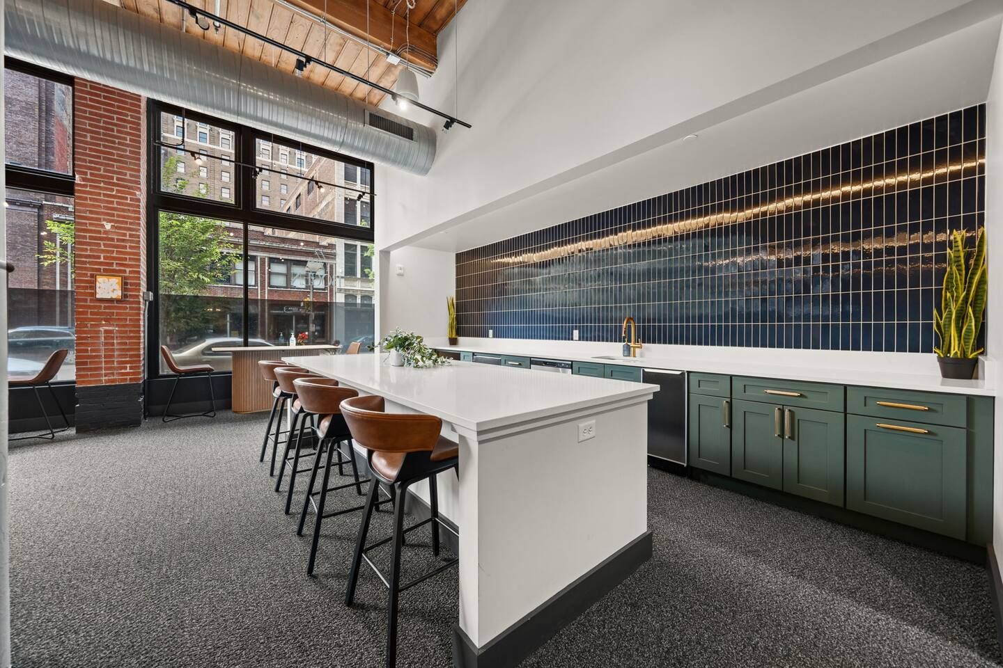 Una cocina moderna con una isla grande, taburetes de bar y vistas de la ciudad a través de amplios ventanales.