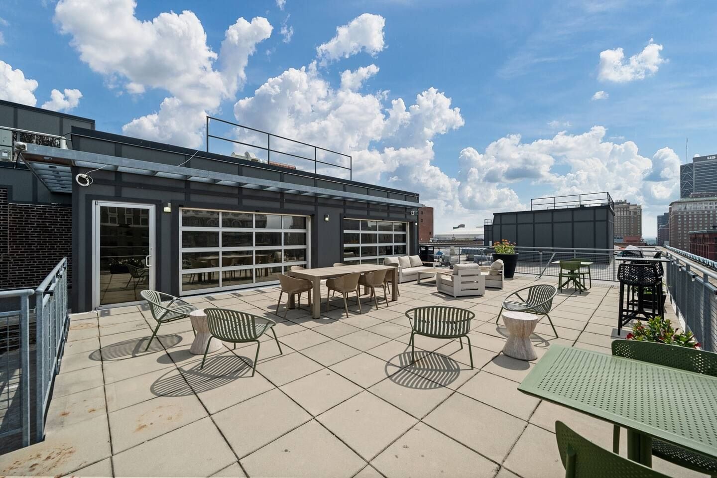 A rooftop terrace with outdoor seating, a glass door entrance, and a city view.