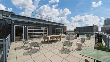 A rooftop terrace with outdoor seating, a glass door entrance, and a city view.