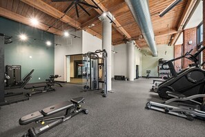 A gym with various exercise equipment, including a treadmill, weight machines, and a squat rack. - Walk Busch Stadium | FREE Parking | Gym | RT Patio (St. Louis)