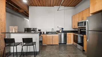 A modern kitchen with a central island, stainless steel appliances, and wooden cabinets.