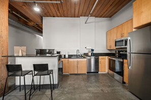 A modern kitchen with a central island, stainless steel appliances, and wooden cabinets.