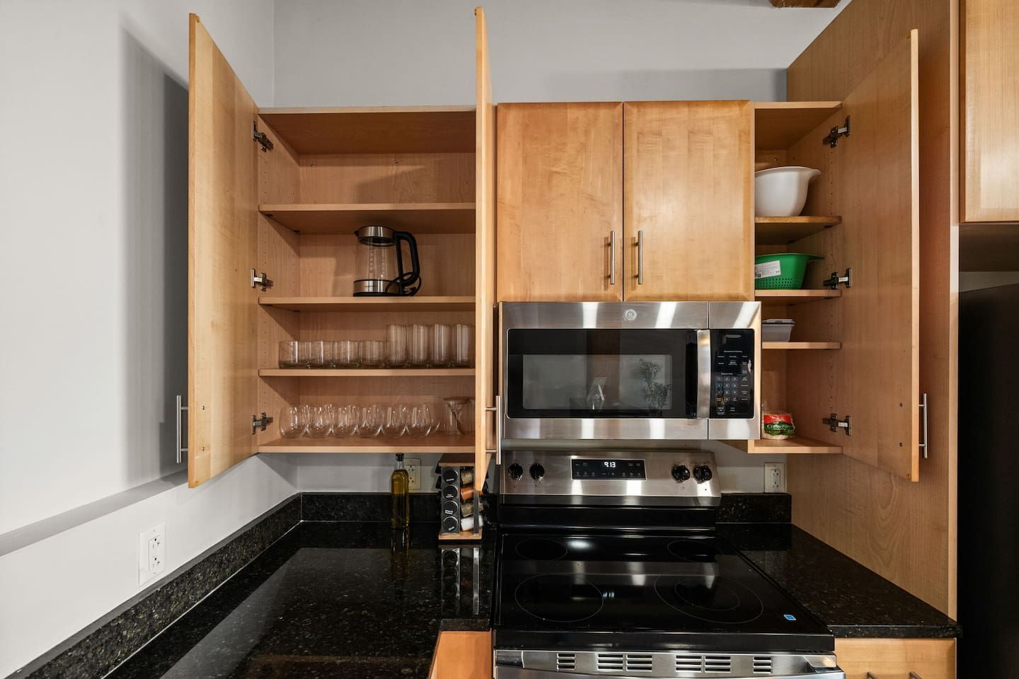 Cocina compacta con armarios de madera, microondas, horno y cafetera.